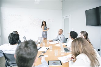 Businesswoman talking at whiteboard in meeting