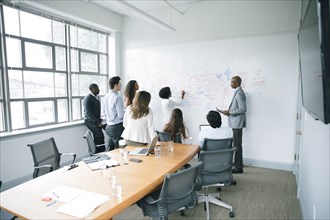 Businesswoman writing on whiteboard in meeting