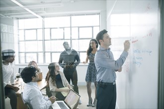 Businessman writing on whiteboard in meeting