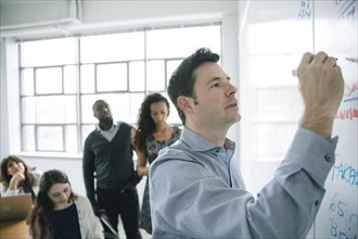 Businessman writing on whiteboard in meeting