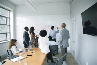 Businessman writing on whiteboard in meeting