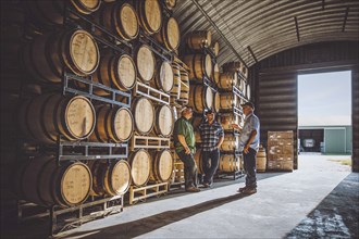 Caucasian men talking near barrels in distillery
