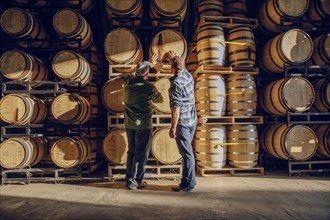 Caucasian men examining barrel in distillery