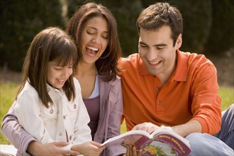 Hispanic family reading outdoors