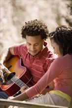 African American man playing guitar for girlfriend