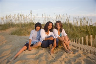 Asian woman and children sitting on beach