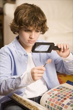 Hispanic boy examining stamp through magnifying glass