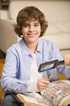 Hispanic boy holding stamp and magnifying glass