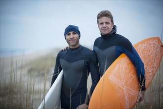 Men wearing wetsuits and carrying surfboards