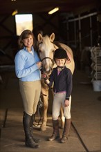 Caucasian girl and trainer standing with horse