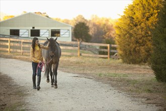 Caucasian girl leading horse on path