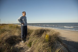 Man standing on sand dune near ocean