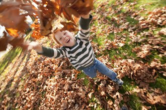 Caucasian boy throwing autumn leaves