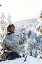 Caucasian woman snowshoeing in remote area taking photographs