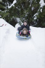 Caucasian children sledding in snow
