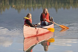 Caucasian mother and daughter canoeing on Lake Edith
