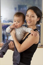 Smiling Korean mother holding baby