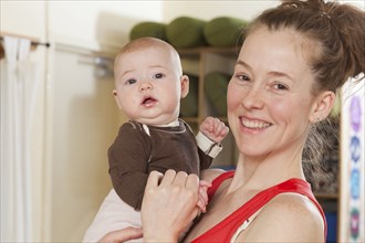 Smiling mother holding baby in yoga studio