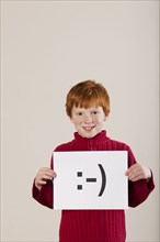 Caucasian boy holding card with smiley face