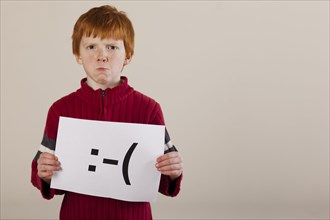 Caucasian boy holding card with sad face