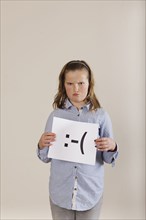 Caucasian boy holding card with sad face