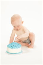 Caucasian baby boy playing with cake