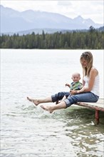 Caucasian mother and baby sitting by lake
