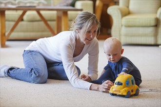 Caucasian mother and baby playing in living room