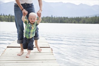 Caucasian mother and baby on dock over lake