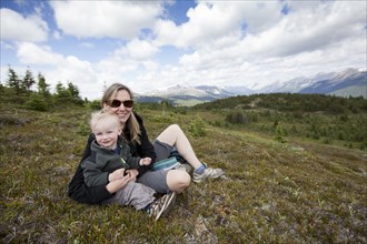 Caucasian mother and son sitting on remote hilltop