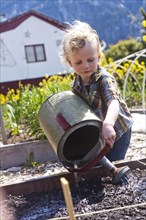 Caucasian boy watering plants in garden