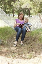 Caucasian mother and son reading in hammock