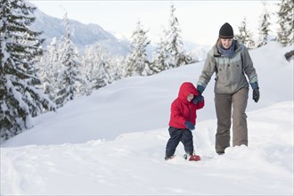 Caucasian mother and son snowshoeing on hillside