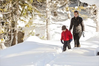 Caucasian mother and son snowshoeing on path