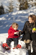 Caucasian mother and son drinking hot cocoa in snow