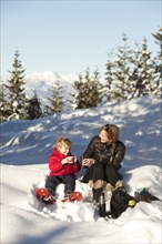 Caucasian mother and son drinking hot cocoa in snow