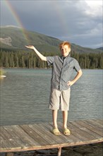 Caucasian boy posing on dock catching rainbow