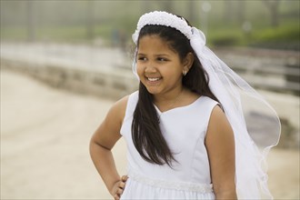Hispanic girl wearing first communion gown and veil