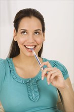 Hispanic woman biting end of pen