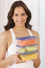 Hispanic woman holding vegetables in plastic storage containers