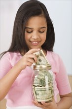 Hispanic girl putting money in jar