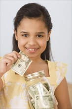 Hispanic girl holding money and jar