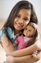 Hispanic girl hugging doll