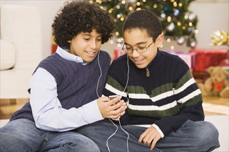 Hispanic brothers sharing mp3 player at Christmas