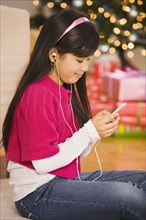 Hispanic girl listening to mp3 player at Christmas