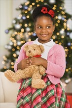 African girl holding teddy bear at Christmas