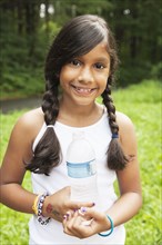 Smiling Hispanic girl holding bottled water