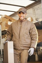 Smiling Hispanic delivery man holding cardboard box