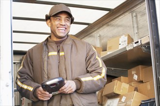 Smiling Hispanic delivery man standing in back of truck