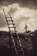 Ladder leaning on stone wall near crucifix